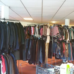 Rekken met tweedehands kleding in verschillende kleuren en maten in de winkel
