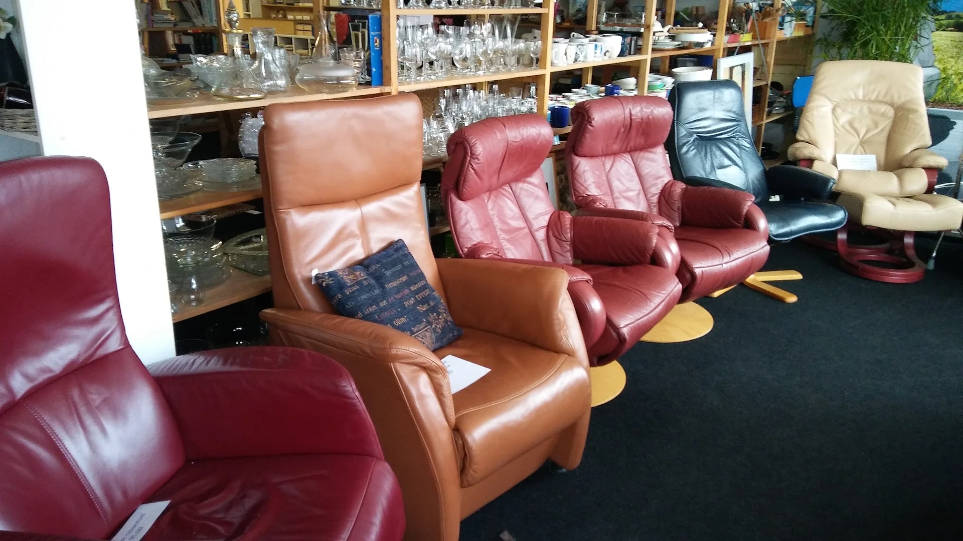 Diverse tweedehands leren fauteuils en relaxstoelen in verschillende kleuren uitgestald in de winkel