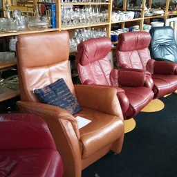 Diverse tweedehands leren fauteuils en relaxstoelen in verschillende kleuren uitgestald in de winkel