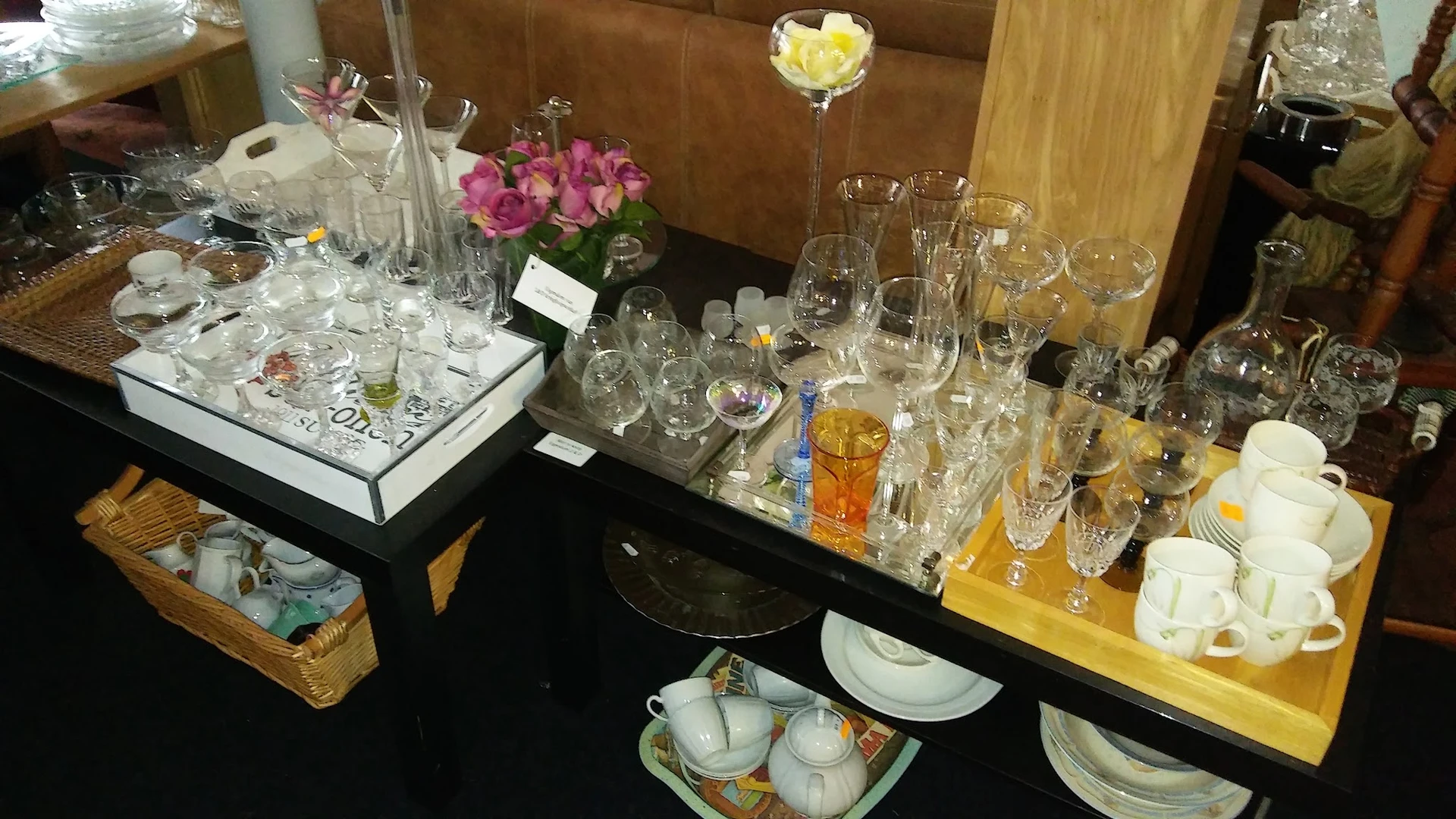 Zwarte tafel met glazen, servies, theepot en bloemen op verschillende hoogten uitgestald