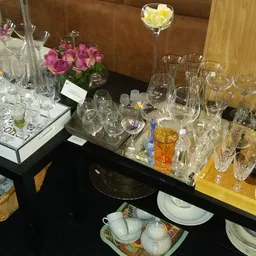 Zwarte tafel met glazen, servies, theepot en bloemen op verschillende hoogten uitgestald