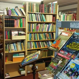 Boekenrekken met veel tweedehands boeken en een displayrek met dvd's en magazines op de winkelvloer