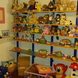 Houten stellingen vol met vintage speelgoed, knuffels en pluchen dieren in verschillende formaten en kleuren