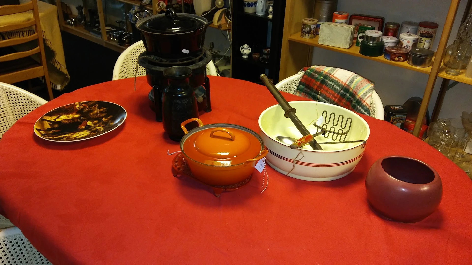 Rood tafelblad met huishoudelijke spullen: gouden pan met deksel, witte schalen en keukengereedschap