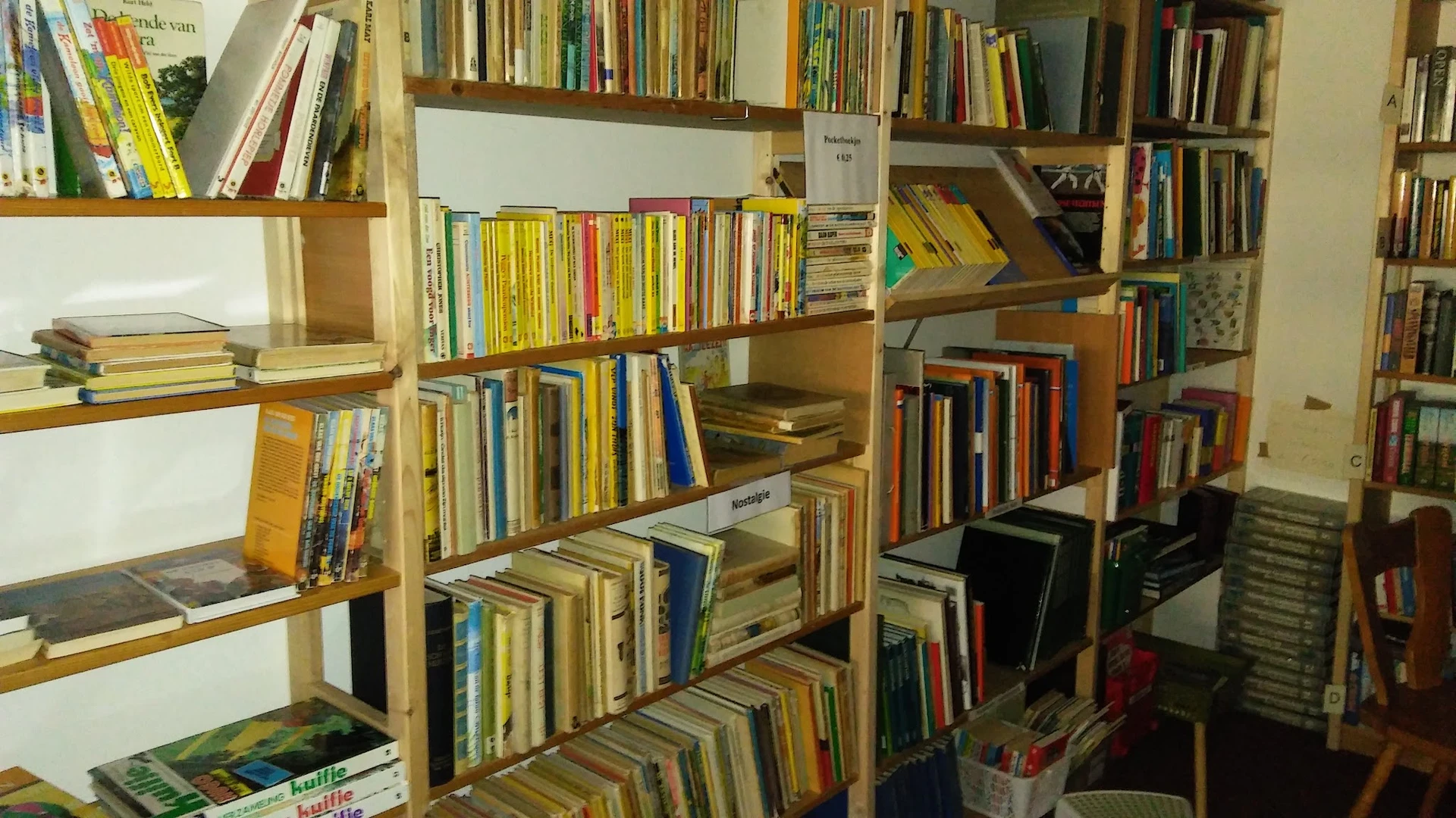 Houten stellingen vol met CD's en DVD's, gerangschikt per plank in de winkel