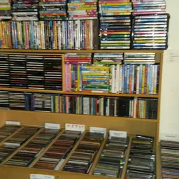 Uitgestalde cd's en dvd's in dozen op een tafel en in rekken tegen de muur.