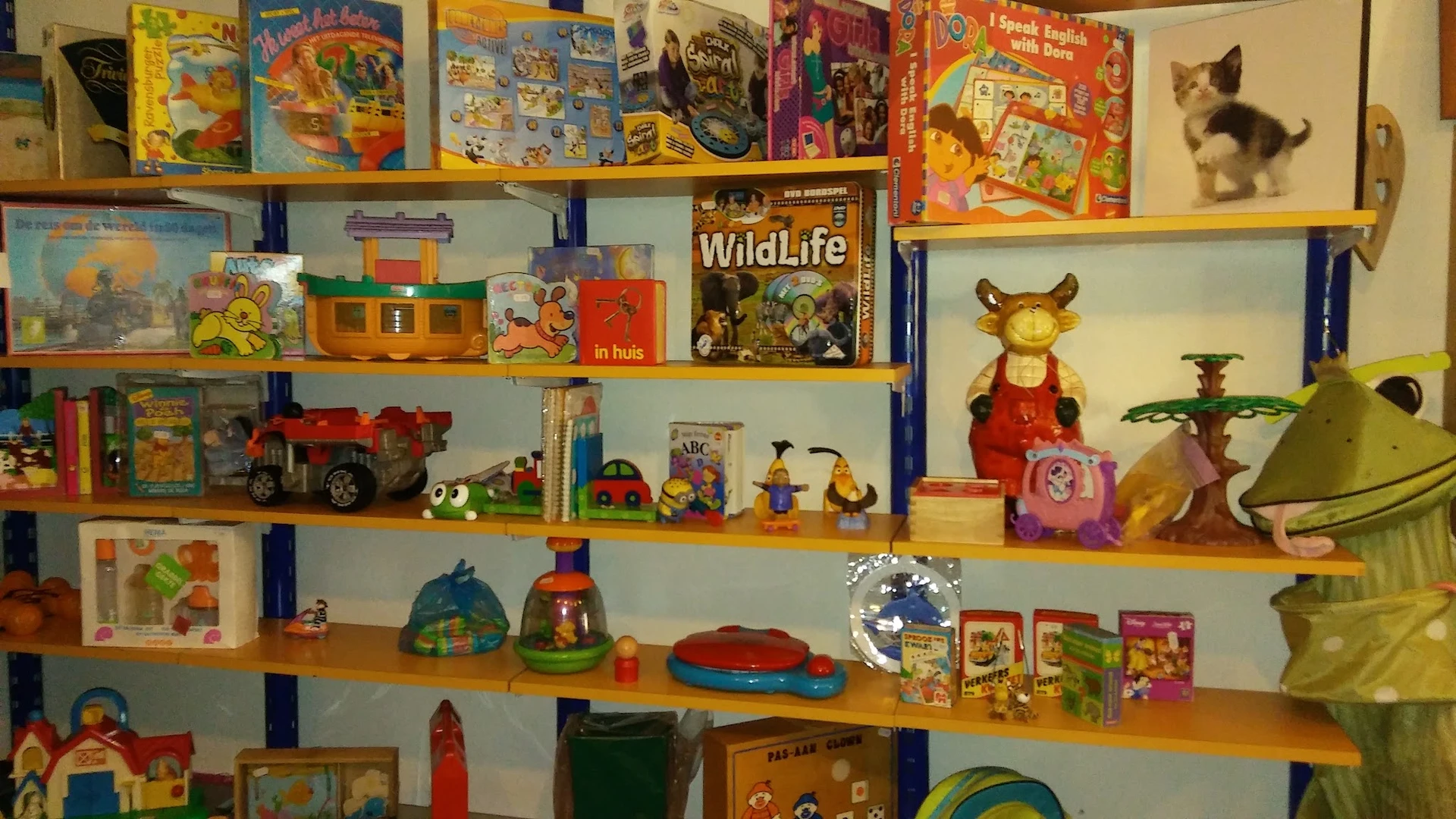 Houten stellingen met speelgoed, boeken, huishoudelijke artikelen en decoraties in een kringloopwinkel