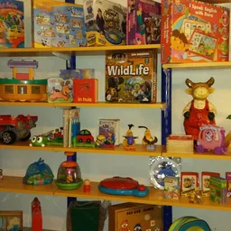 Houten stellingen met speelgoed, boeken, huishoudelijke artikelen en decoraties in een kringloopwinkel