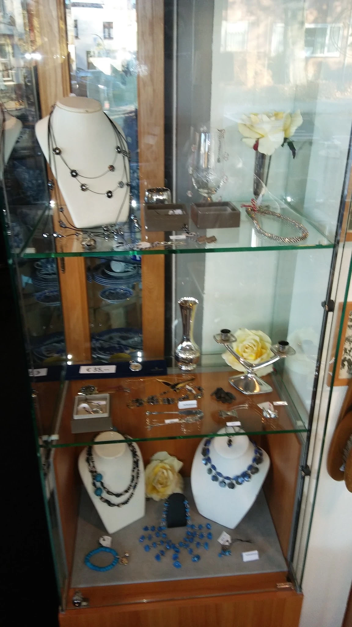 Vitrinekasten met diverse tweedehands artikelen: sieraden, decoratieve objecten en huishoudartikelen