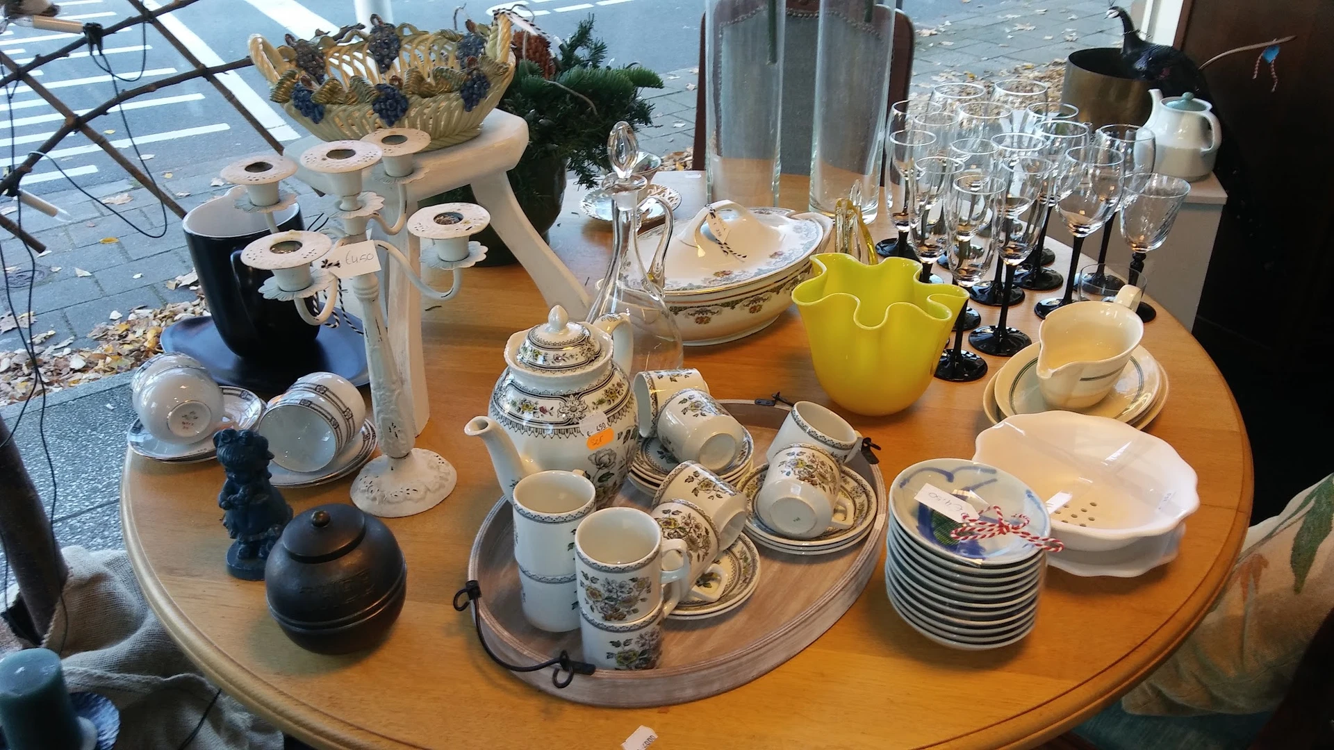 Uitstalling van wit en crème porseleinen serviesgoed, kopjes, schalen en theepot op houten tafel