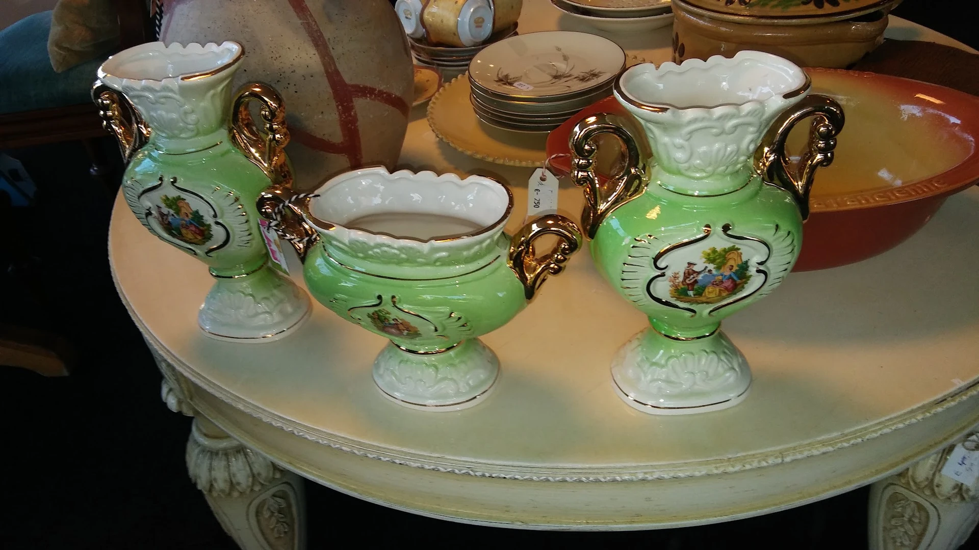 Groen servies met gouden handvatten en witte rand op een tafel, bestaande uit kommen en kannen