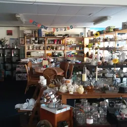 Winkelinterieur met houten meubels, servies en huishoudelijke spullen op tafels en in stellingen tegen de muur