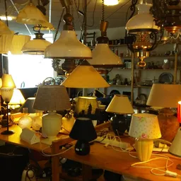 Diverse lampen en lampenkappen uitgestald op tafels in de winkel
