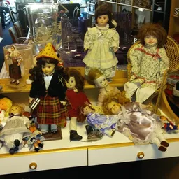 Verzameling antieke en vintage poppen in een vitrinekast, met verschillende kleertjes en accessoires uitgestald