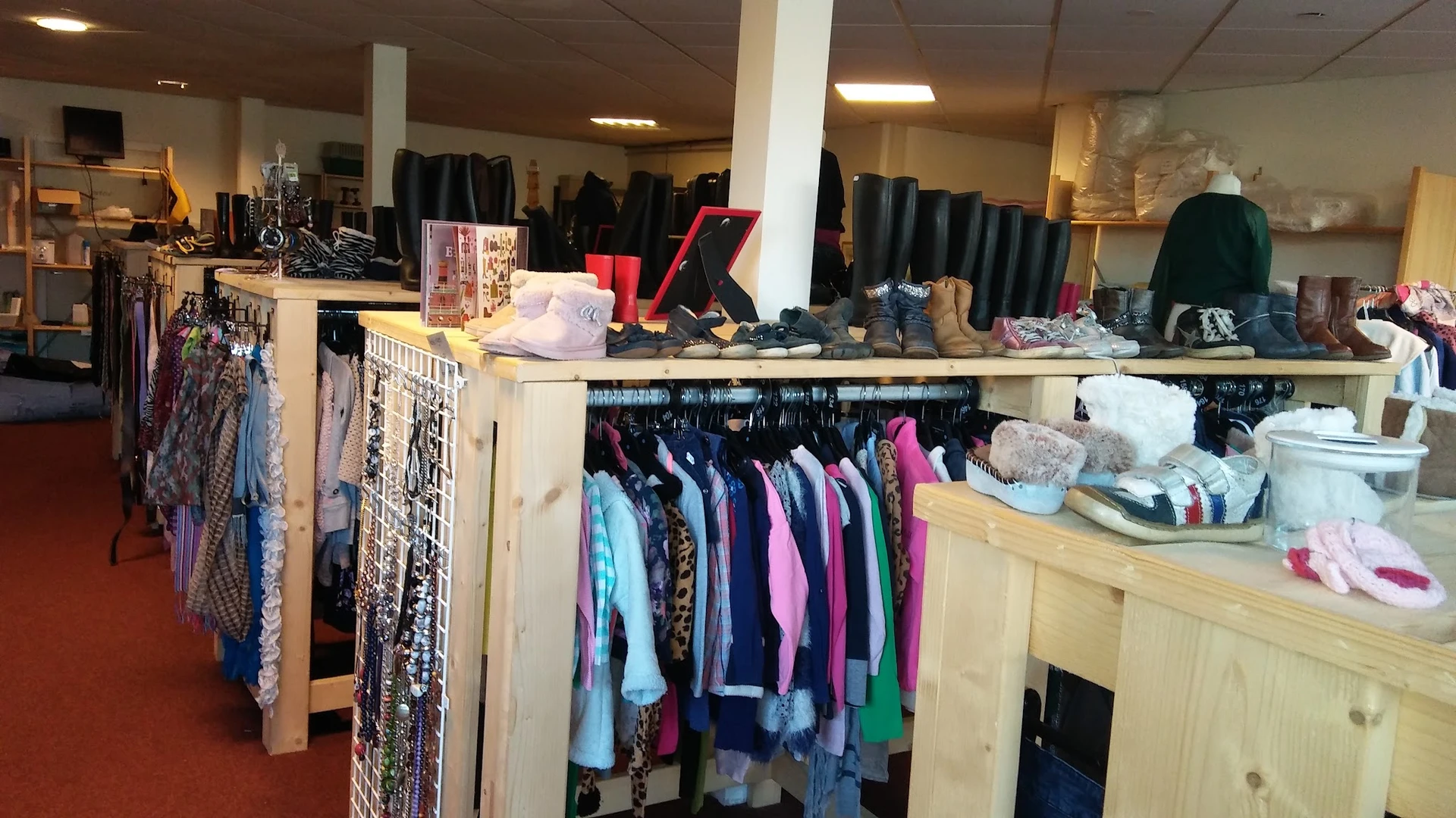 Rekken en toonbanken met tweedehands kleding, schoenen en accessoires in verschiedene kleuren
