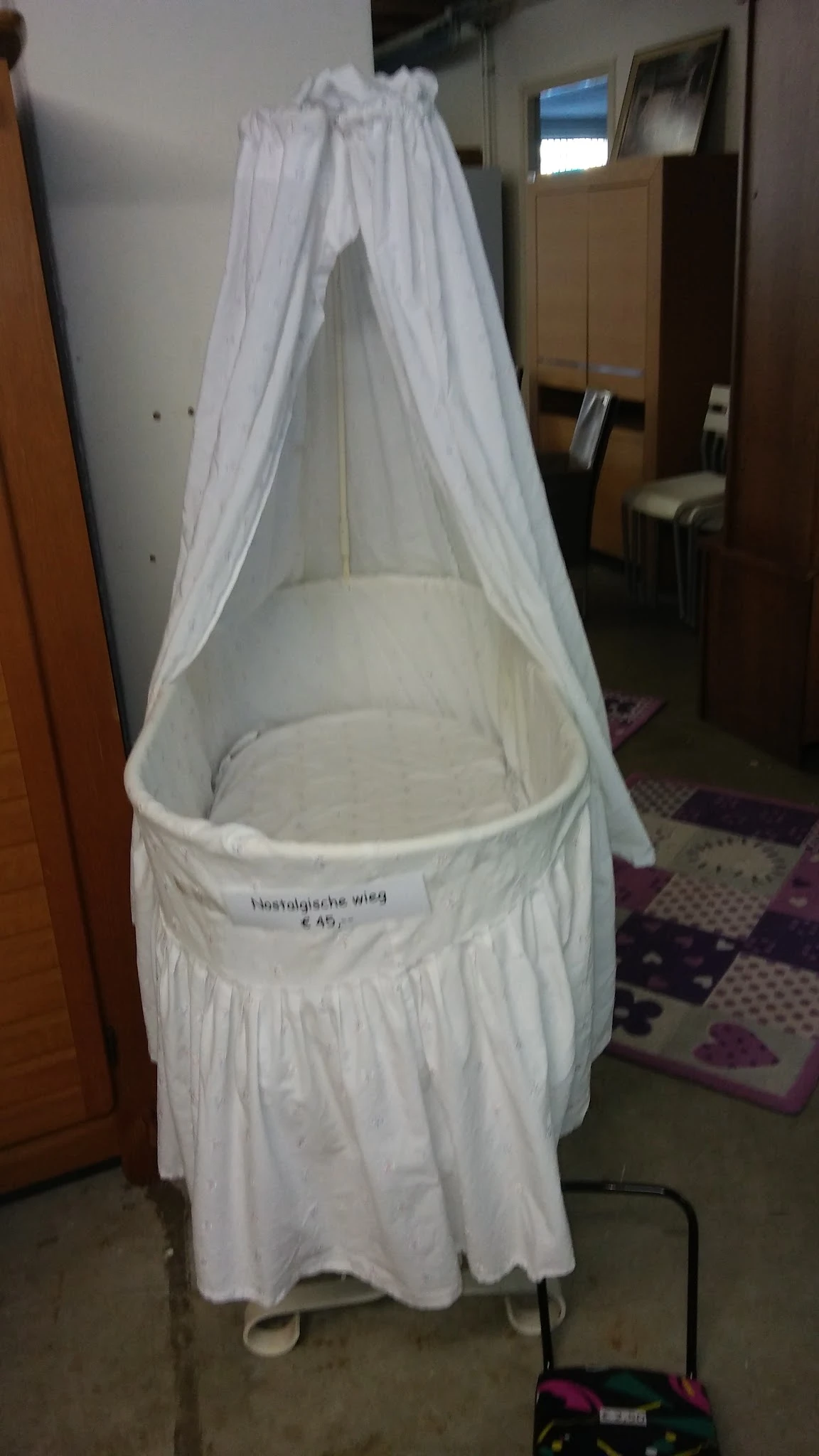 Witte babybed of wieg met gaas/muggennet en een prijskaartje