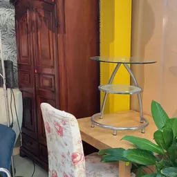 Glazen tafel op aluminium frame met drie niveaus, in een interieur met gele panelen op de achtergrond