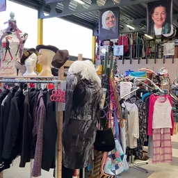 Rekken met tweedehands dames- en kinderkleding, inclusief jassen, shirts en broeken in verschillende kleuren