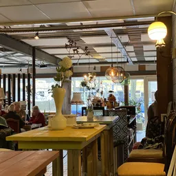 Winkelvloer met gele tafel, hangende lampen, decoratie, en klanten aan het winkelen