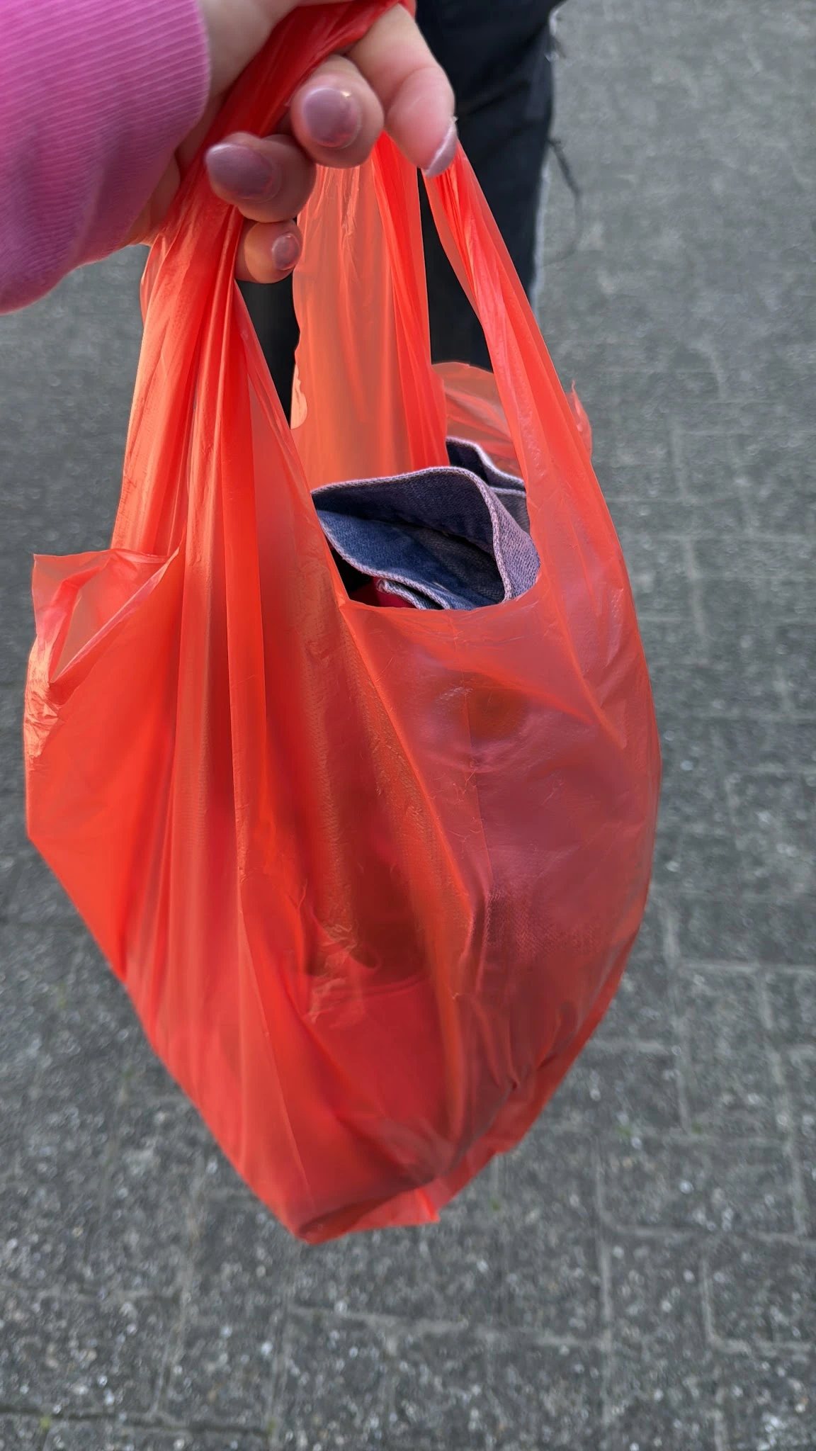Rode plastic boodschappentas met donkerblauwe binnenzijde en een gat in de stof