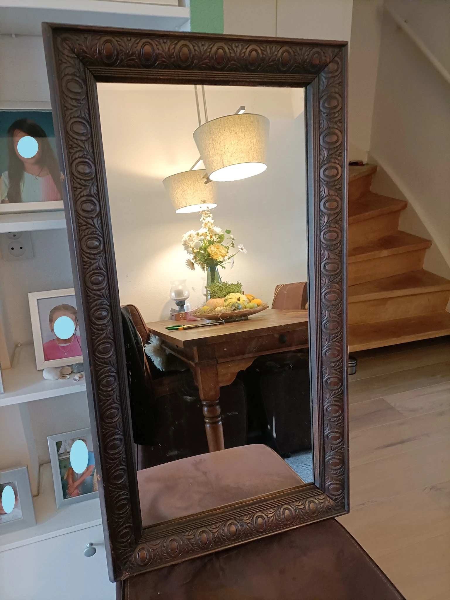 Houten tafel met bloemen in een vaas, fruitschaal en hangende tafellamp in een ingerichte kamer