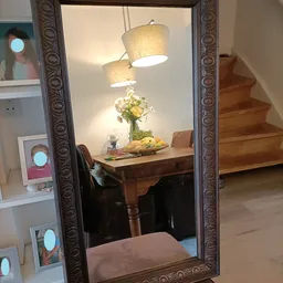 Houten tafel met bloemen in een vaas, fruitschaal en hangende tafellamp in een ingerichte kamer