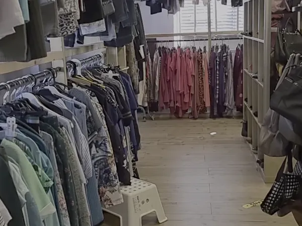 Winkelinterieur met kledingrekken vol tweedehands kleding in verschillende kleuren