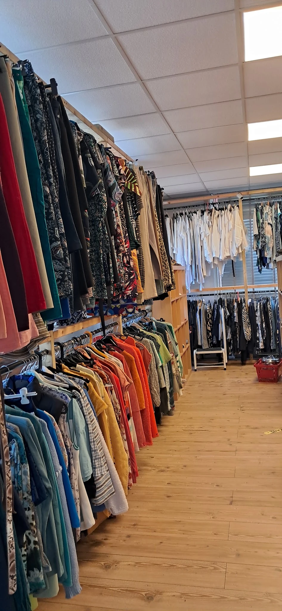 Rekken met tweedehands kleding in verschillende kleuren en stijlen in een kringloopwinkel