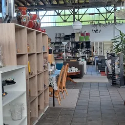 Overzicht van de winkelvloer met houten stellingen, houten stoelen, tafels en diverse inrichting en meubelen