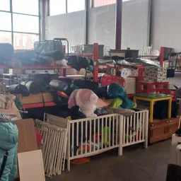 Winkelvloer met speelgoed en babyartikelen, waaronder een witte babybox met kleurrijke voorwerpen erin