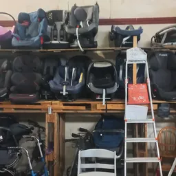 Houten stellingen met uitgestalde autostoeltjes, kinderwagens en ander babyverzorgingsmateriaal