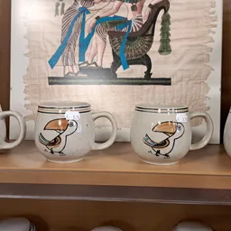 Uitgestalde serviesset met bekers en een decoratieve Egyptische poster op de achtergrond