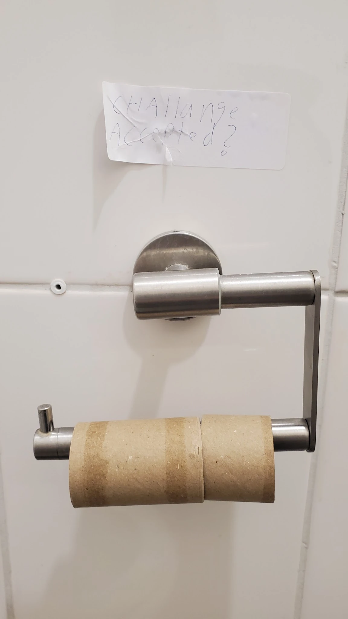 Close-up van een roestvrijstalen toiletpapierdispenser aan een witte wand