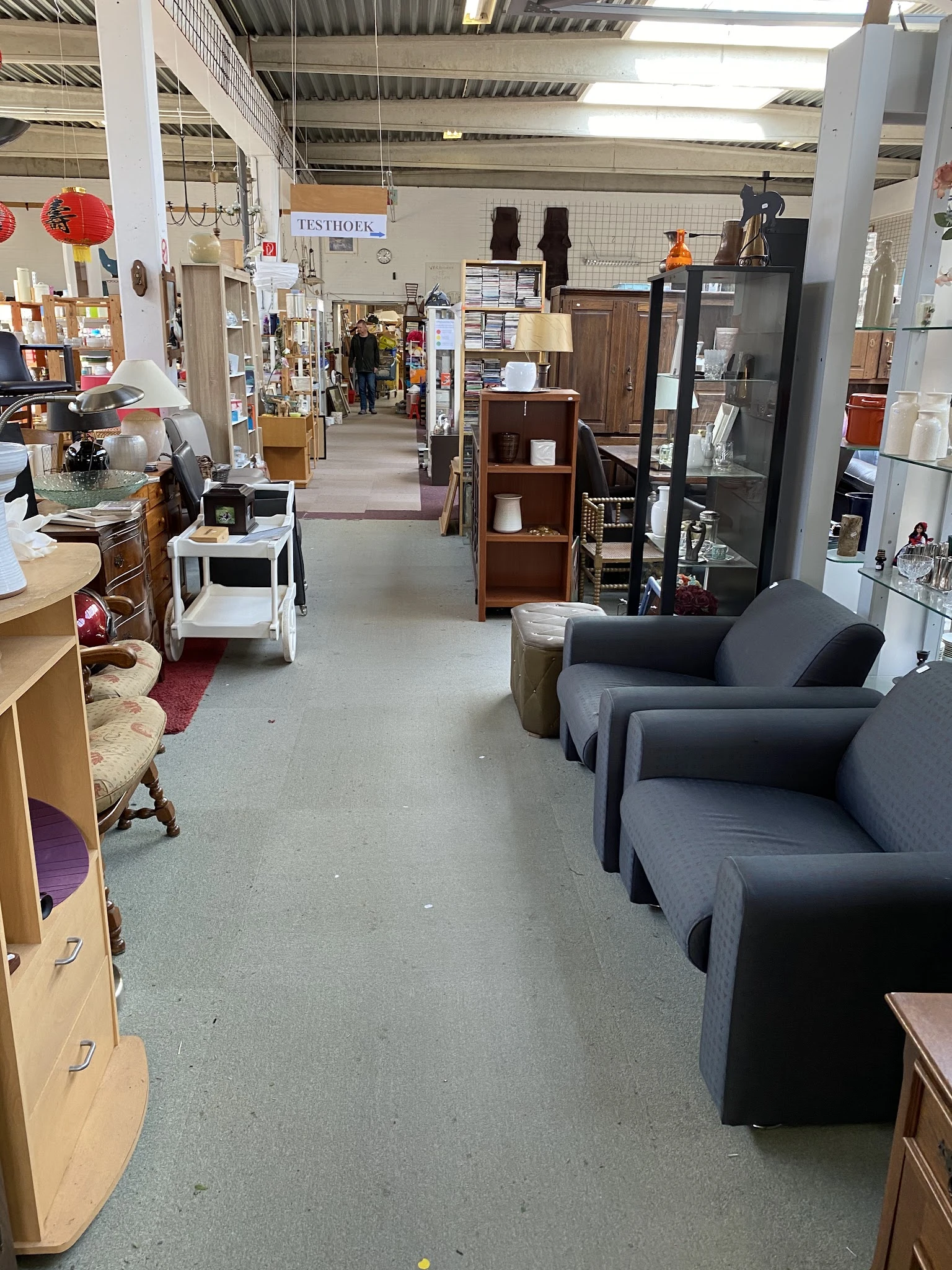 Winkelvloer van kringloopwinkel met meubels, stellingen en diverse artikelen langs het pad