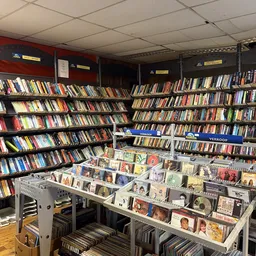 Winkelbinnenkant met hoge stellingen vol cd's en dvd's, en onderaan uitstalkastjes met muziek- en mediaverzamelingen.