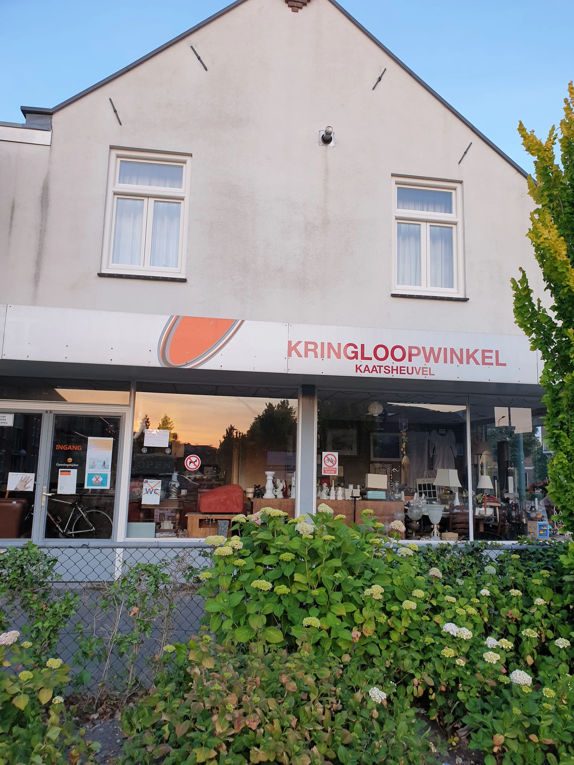 Gevel van kringloopwinkel Kaatsheuvel met logo en grote ramen waarachter spullen zichtbaar zijn