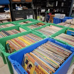 Groene en blauwe plastic bakken vol met cd's en vinyl records, gesorteerd in rijen