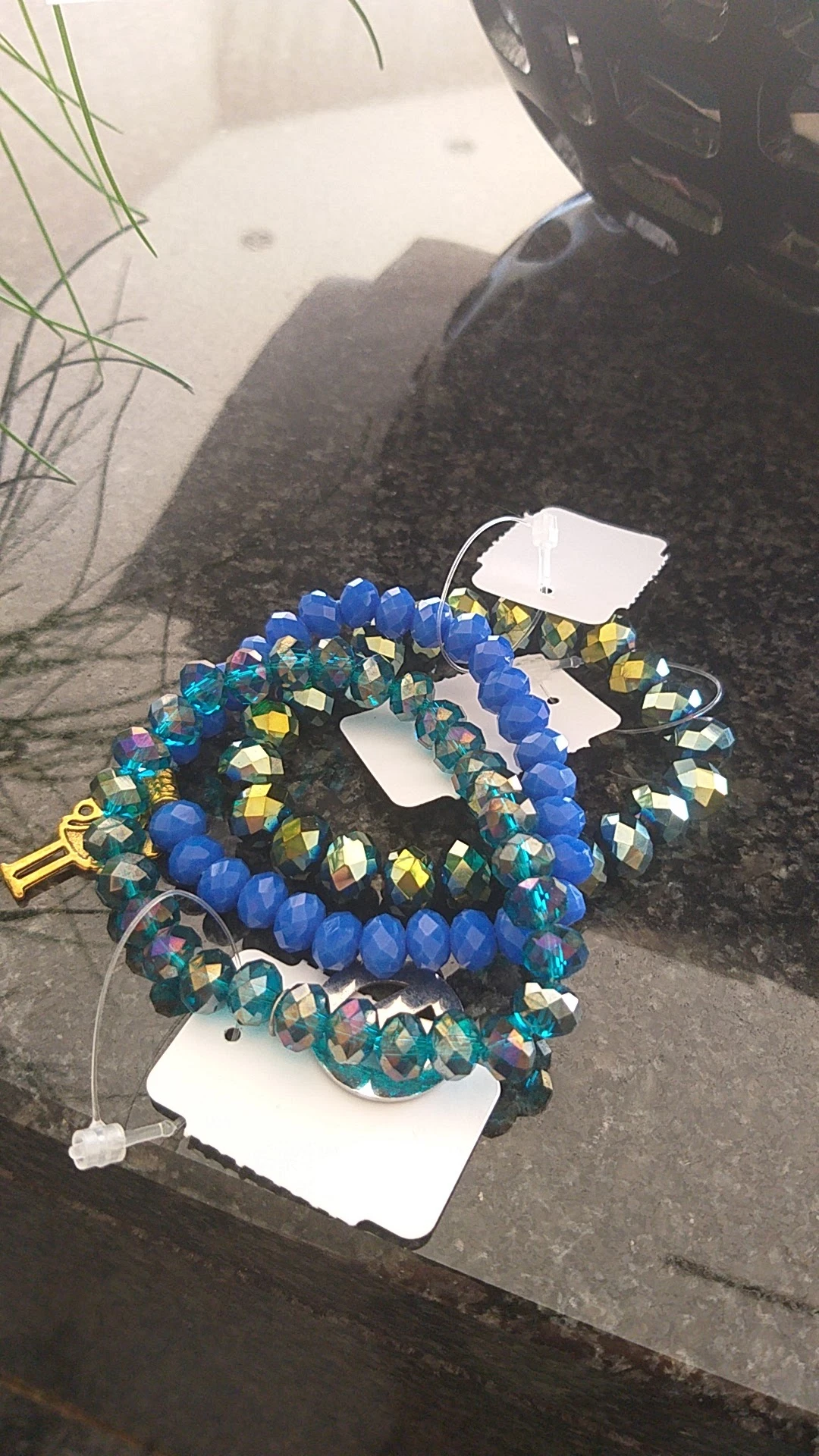 Blauwe kralen armbanden met goud en groen accent, op witte etiketten