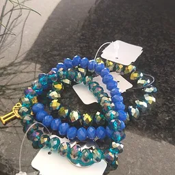 Blauwe kralen armbanden met goud en groen accent, op witte etiketten