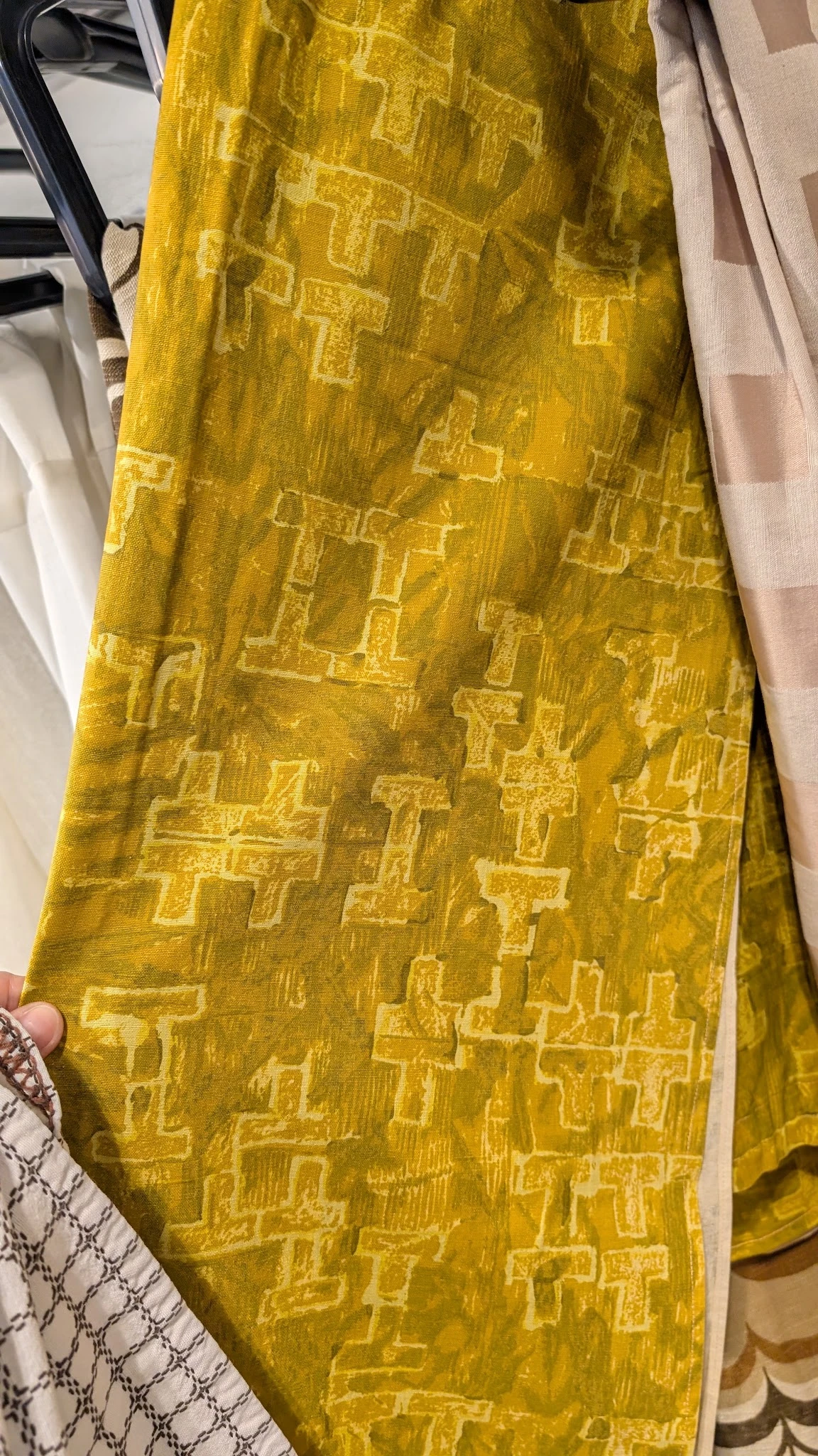 Geel gestructureerd textielstuk met geometrisch patroon, vastgehouden in hand