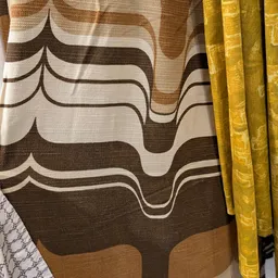 Golvend patroon op bruine en crème stoffen, mogelijk gordijnen of bekleding met gele gordijnen ernaast
