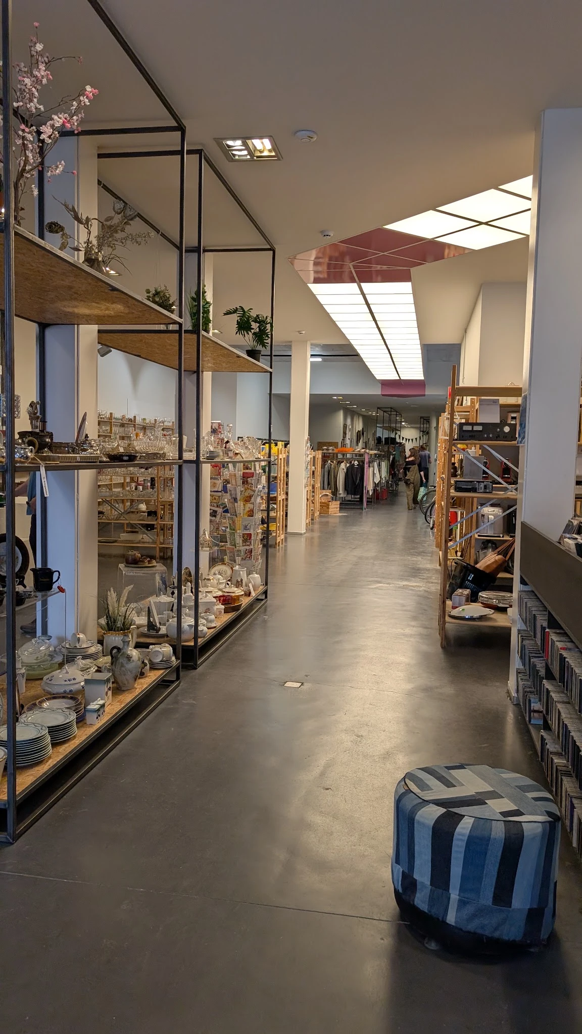 Winkelvloer van kringloopwinkel met stellingen, rekken met kleding en diverse spullen links en rechts