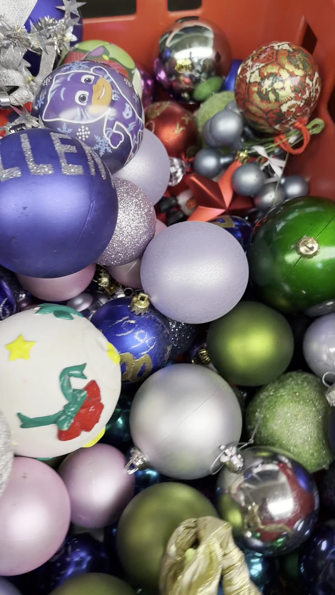 Verzameling kerstballen in verschillende kleuren en designs, waaronder paars, zilver, groen en wit met glitter en patronen