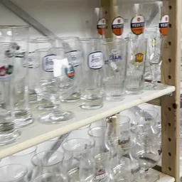 Glazen drinkglazen en bekers op winkelschappen, deels onscherp gefotografeerd