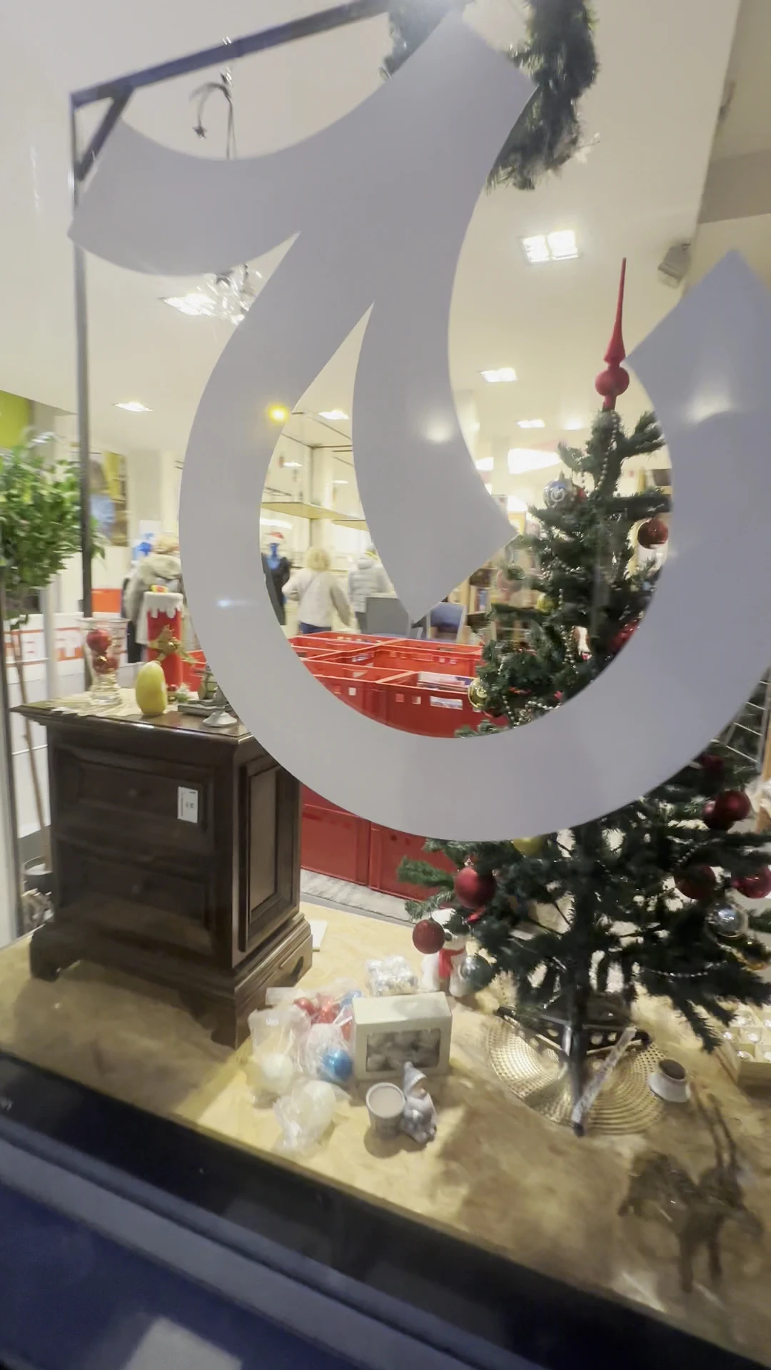 Winkelinterieur met grote witte ring-decoratie en kerstboom met rode ballen