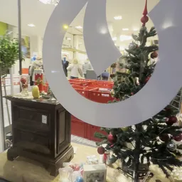 Winkelinterieur met grote witte ring-decoratie en kerstboom met rode ballen