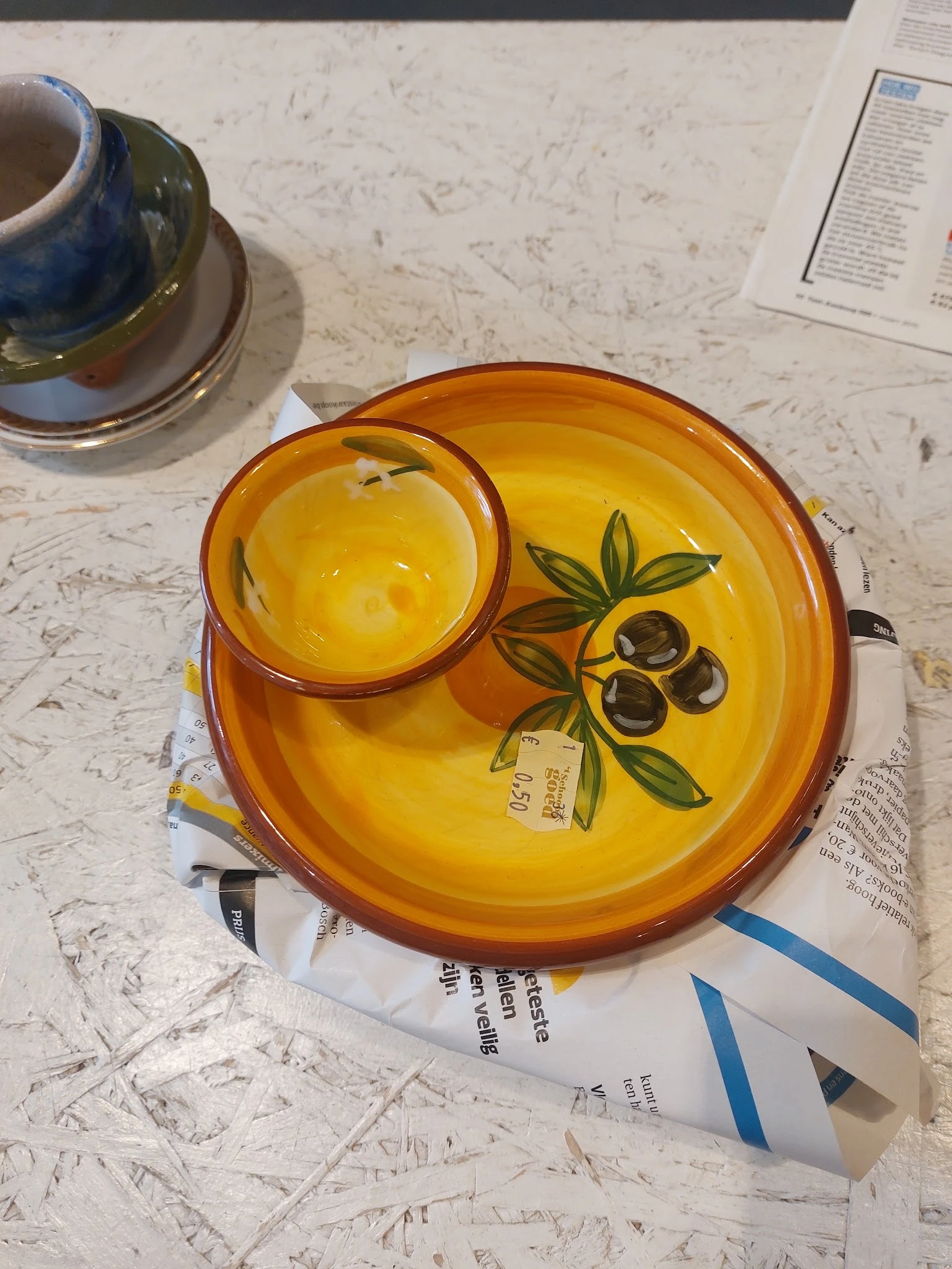 Geel servies met olijfmotief: ronde schaal met kom op marmeren tafel