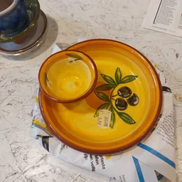 Geel servies met olijfmotief: ronde schaal met kom op marmeren tafel