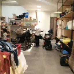 Rommelig winkelinterieur met stellingen, kleding, fietsen en diverse spullen verspreid over de vloer