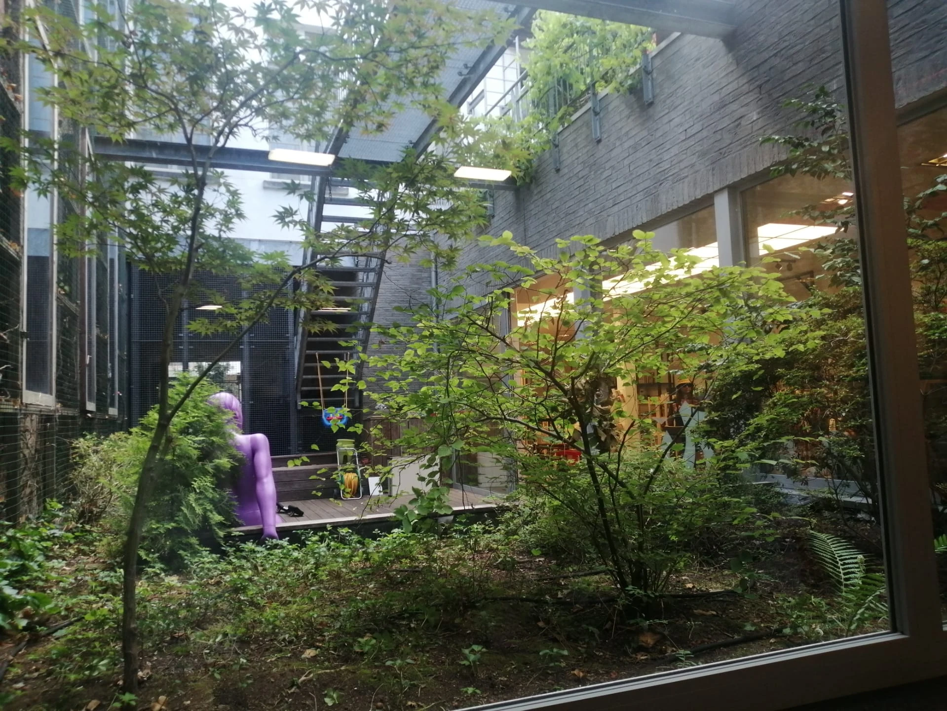 Binnentuin of courtyard met veel groen, bomen en planten tussen bakstenen gebouwen